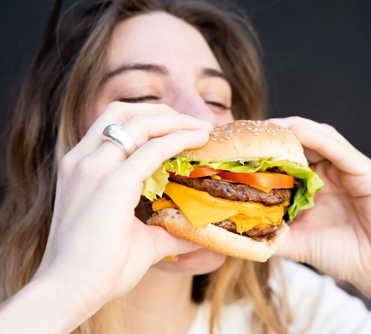 Persona disfrutando una hamburguesa Alido