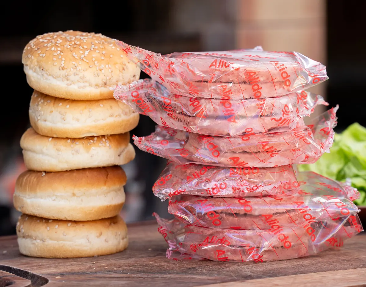 Hamburguesas Alido envasadas y apiladas junto a panes
